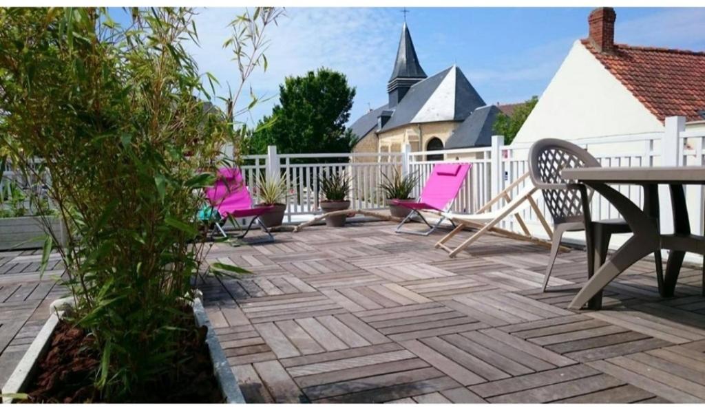 une terrasse avec des chaises roses, une table et une clôture dans l'établissement WISSANT - Appartement avec grande terrasse, à Wissant