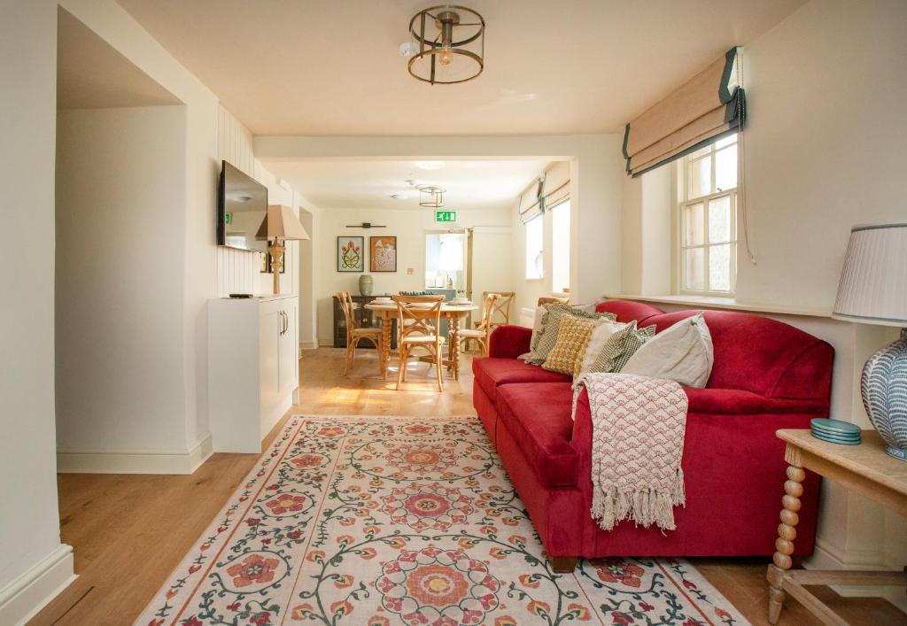 a living room with a red couch and a table at Luxurious Town Centre Apartments in Cirencester