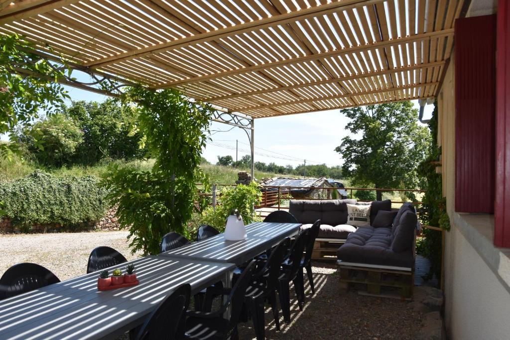une table et des chaises sous une pergola en bois dans l'établissement Les Carbonniers, à Saint-André-de-Najac
