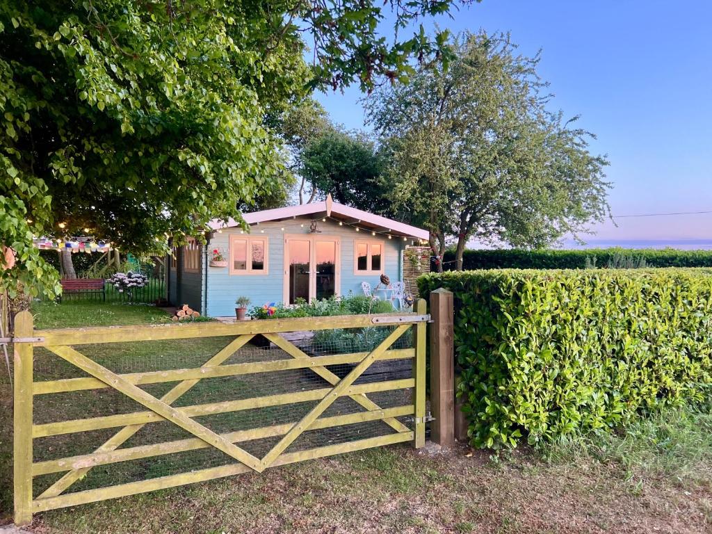 a gate in front of a house with a fence at Tranquil Norfolk Log Cabin - Stunning Rural Sunset Views in Weston Longville