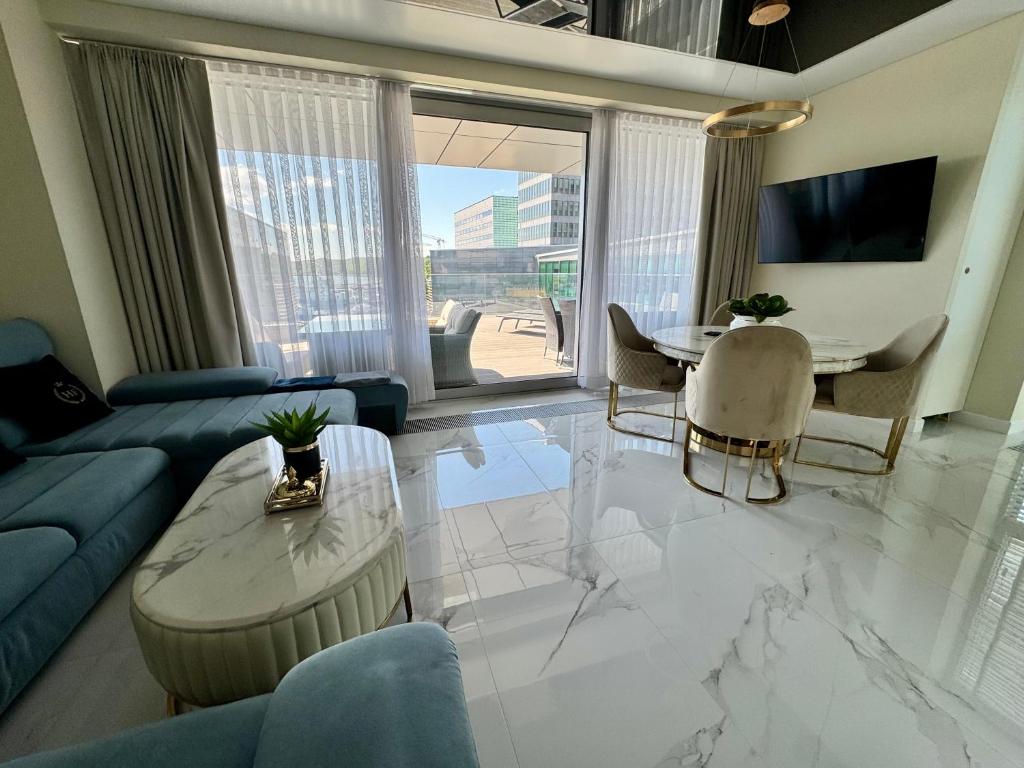 ein Wohnzimmer mit einem blauen Sofa und einem Tisch in der Unterkunft Apartament Faltom 26 Yacht Park z tarasem in Gdynia