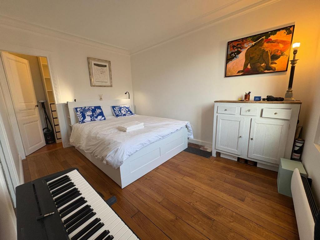 - une chambre avec un lit blanc et un piano dans l'établissement 2 pièces lumineux à deux pas de la Tour Eiffel, à Paris