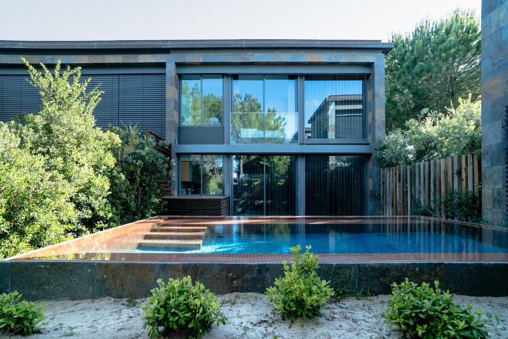 a swimming pool in front of a house at Designer Villa in Comporta in Troia