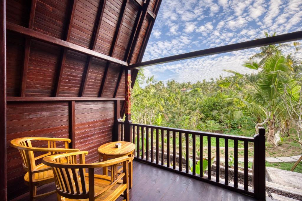 a balcony with two chairs and a table at Kelingking Terrace Cottage in batumadeg