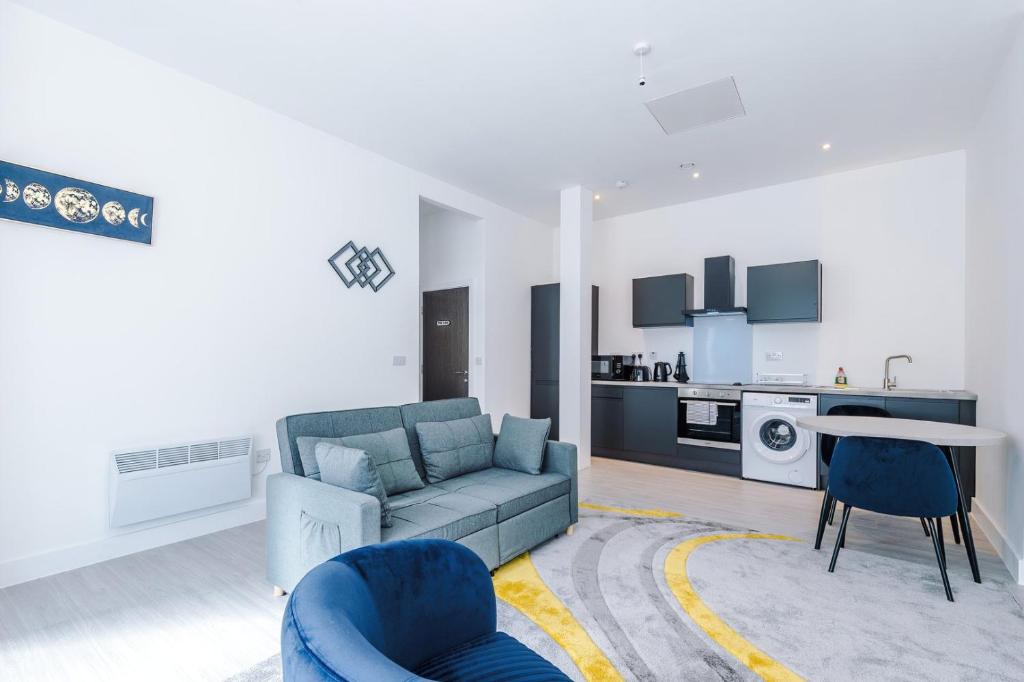 a living room with a blue couch and a kitchen at Cohost Partners Cozy Stay Heart of Warrington in Warrington