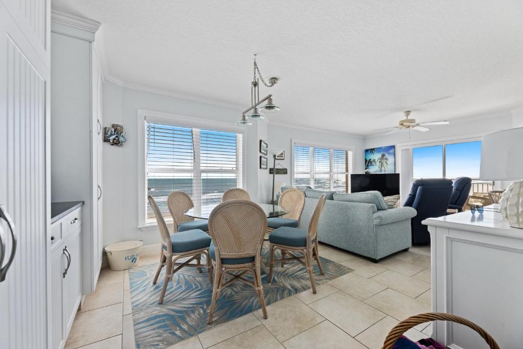 a dining room and living room with a table and chairs at Palm House 3B with oceanfront views, pool, and private beach access in New Smyrna Beach