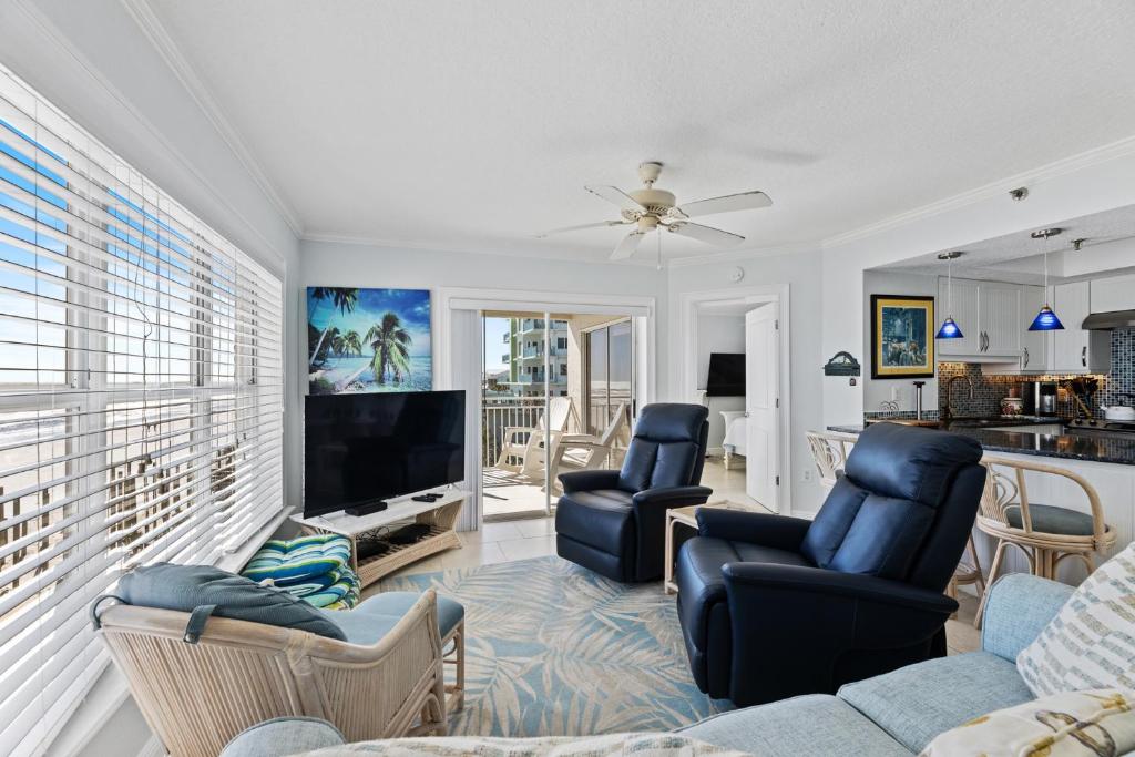 a living room with a couch and chairs and a tv at Palm House 3B with oceanfront views, pool, and private beach access in New Smyrna Beach