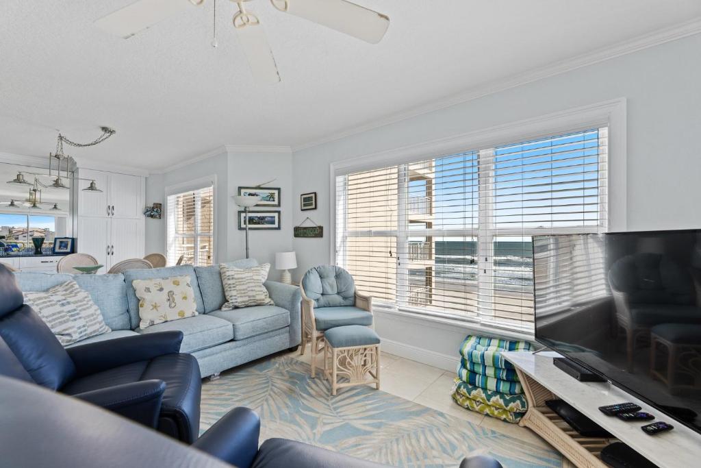 a living room with a blue couch and a tv at Palm House 3B with oceanfront views, pool, and private beach access in New Smyrna Beach
