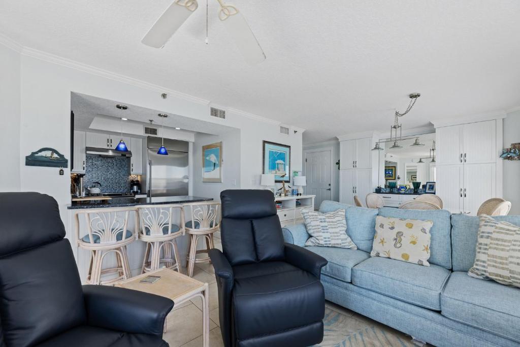 a living room with a blue couch and a kitchen at Palm House 3B with oceanfront views, pool, and private beach access in New Smyrna Beach