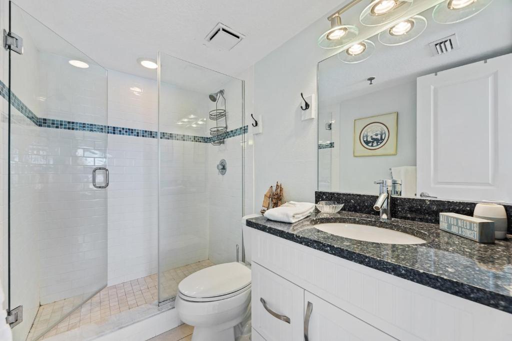 a bathroom with a toilet and a shower and a sink at Palm House 3B with oceanfront views, pool, and private beach access in New Smyrna Beach