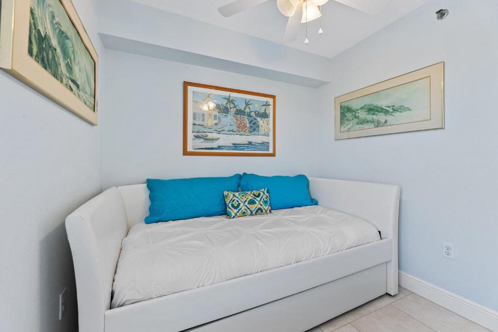 a white couch in a room with paintings on the wall at Palm House 3B with oceanfront views, pool, and private beach access in New Smyrna Beach