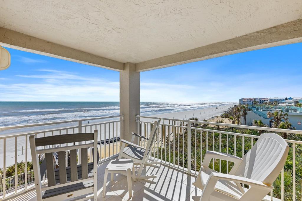 a balcony with two chairs and a view of the beach at Palm House 3B with oceanfront views, pool, and private beach access in New Smyrna Beach