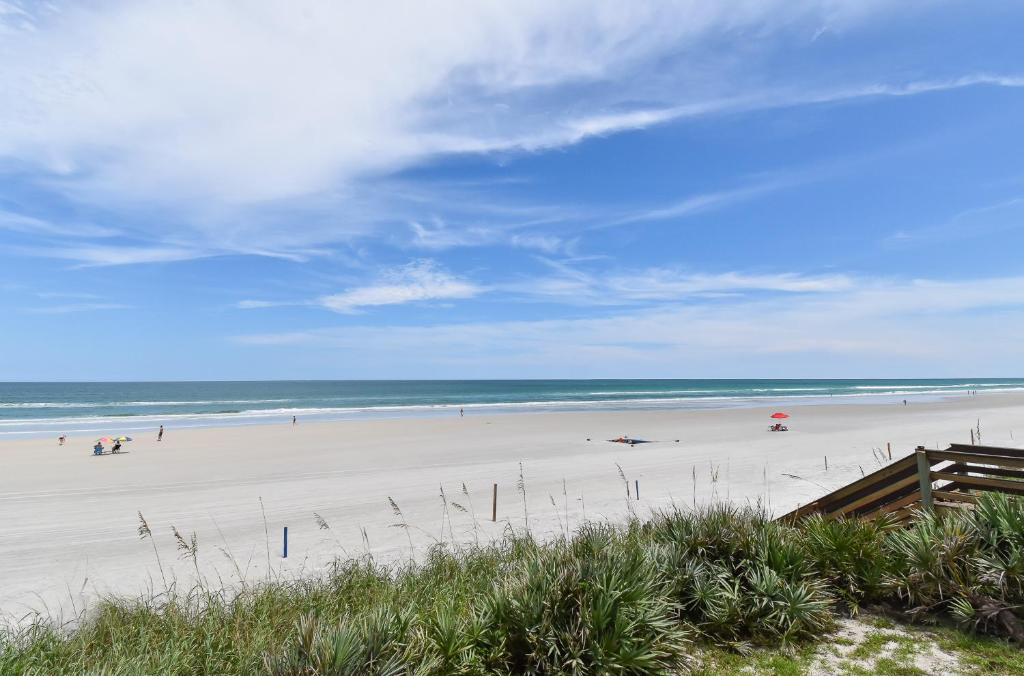 a beach with people on the sand and the ocean at Palm House 3B with oceanfront views, pool, and private beach access in New Smyrna Beach