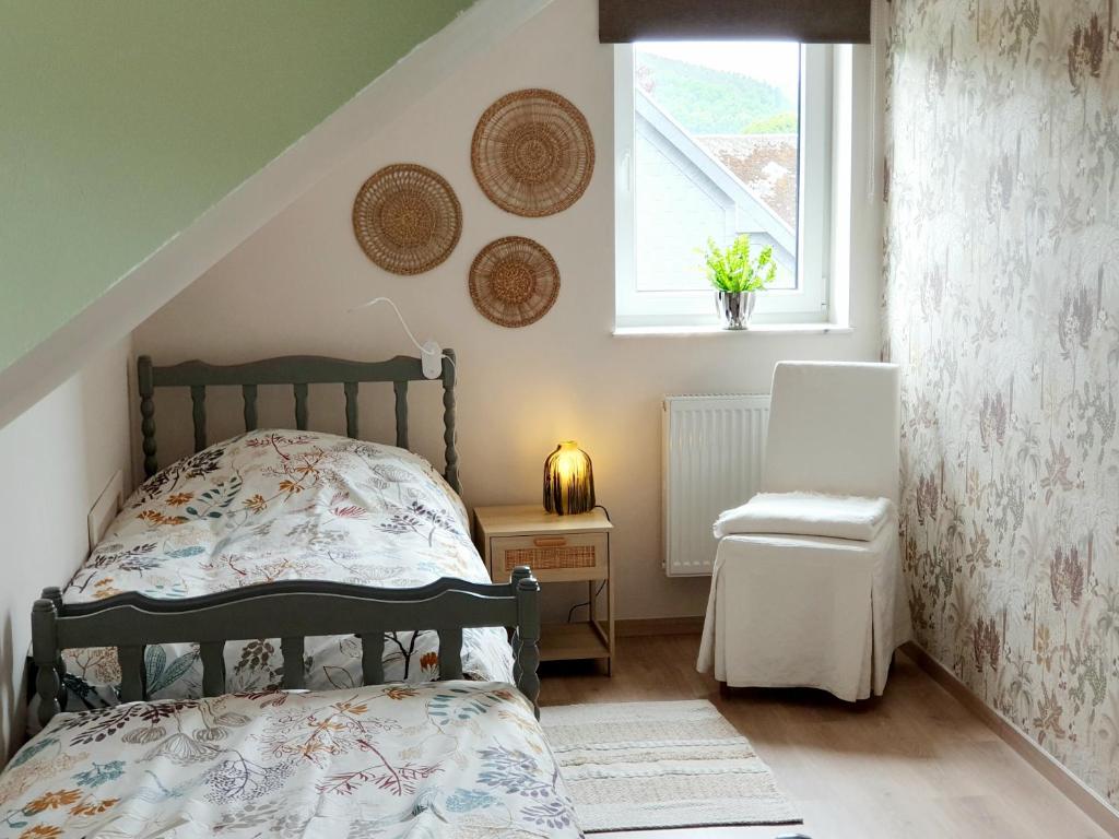 Un dormitorio con una cama y una ventana y una silla. en Gîte Au Val de Belvâ, en Malmedy