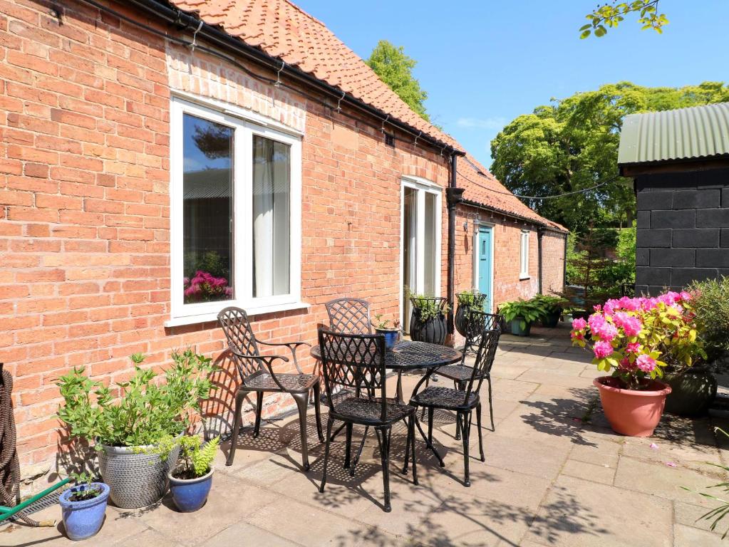 a patio with a table and chairs and flowers at Petal Cottage in Laxton
