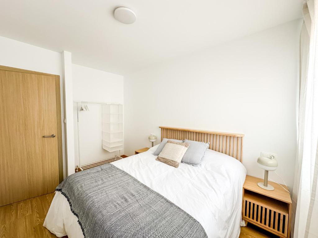a bedroom with a large bed with white sheets at Apartamento Nosa Terra by ALÔGA in Cee