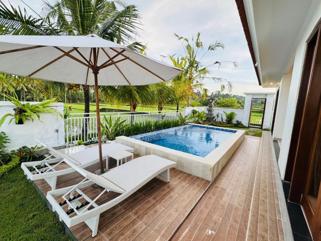 a swimming pool with an umbrella and two lounge chairs and a swimming pool at Villa in Ubud