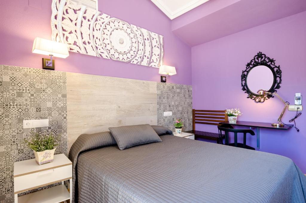 Dormitorio púrpura con cama y espejo en Las Abadías, en Mérida