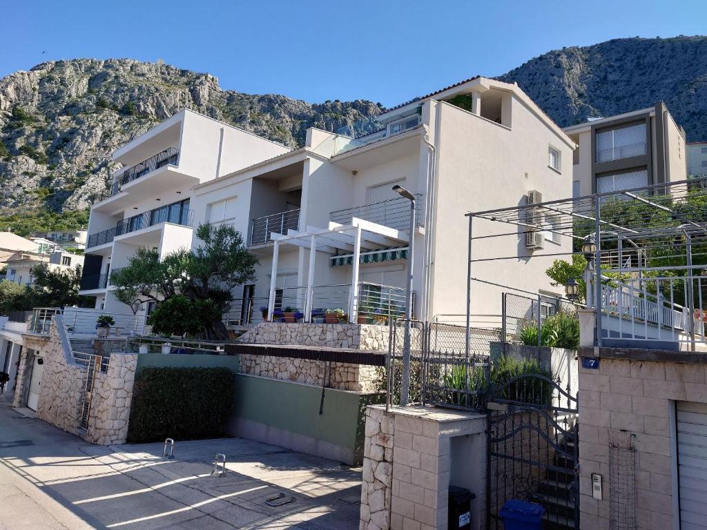 una casa bianca con una montagna sullo sfondo di Apartment Sreta a Omiš (Almissa)