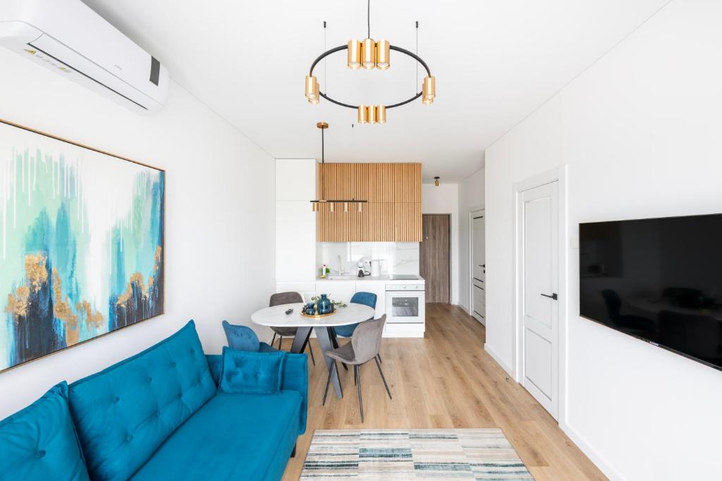 a living room with a blue couch and a table at City Center Apartamentai Šatrijos g in Vilnius