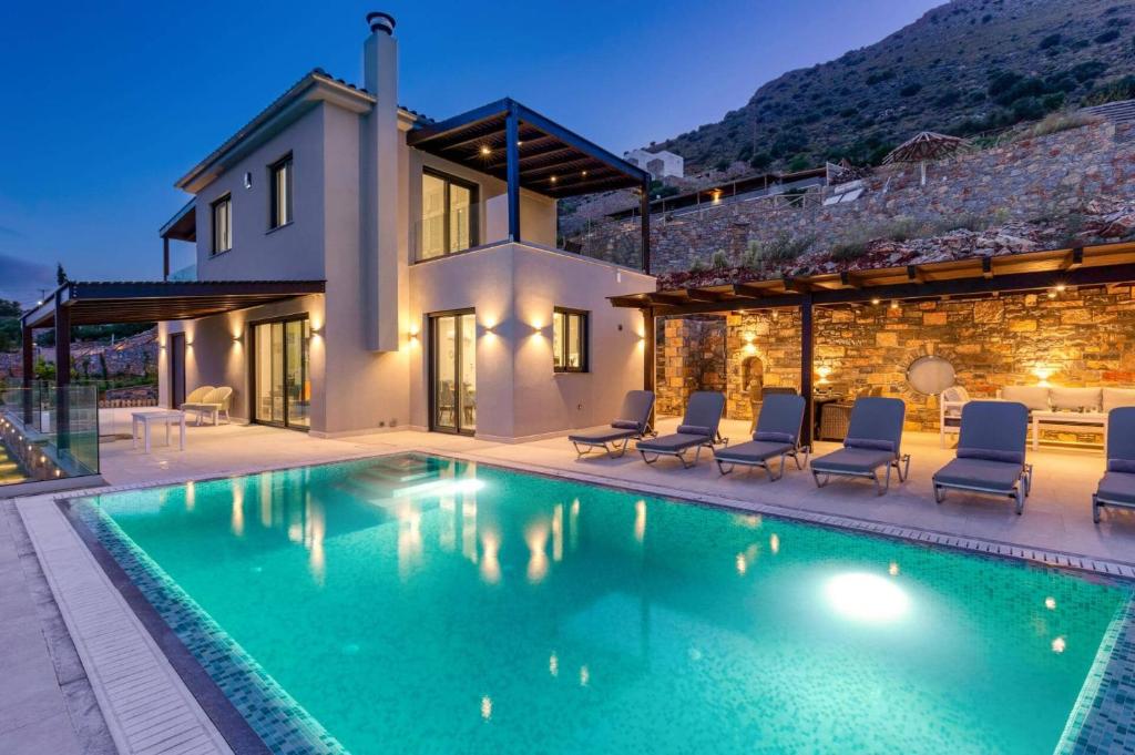 a house with a swimming pool in front of a house at Villa Lela Seaview by Villa Plus in Chavgas