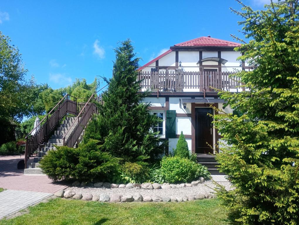 a large white house with a balcony and stairs at Agroturystyka Kaczeniec in Ustronie Morskie