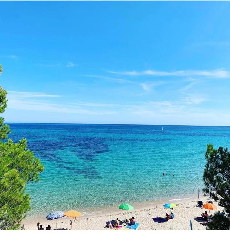 a beach with umbrellas and people in the water at Casa Capinera in Pula