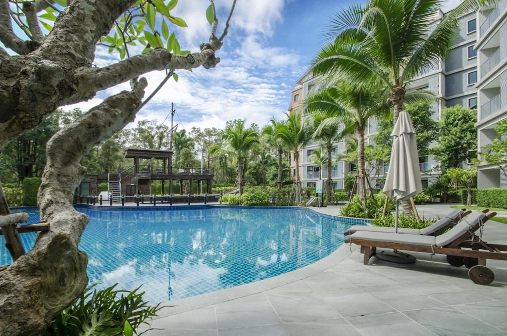 einen Pool in einem Resort mit einer Chaiselongue und einem Sonnenschirm in der Unterkunft G16 Title Naiyang 36м2Ватсап669З5В2I976 in Nai Yang Beach