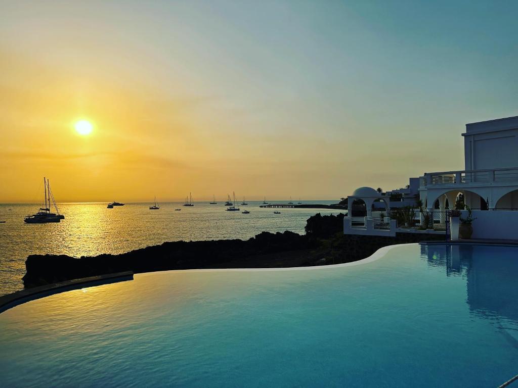 a swimming pool with a view of the ocean at sunset at Hotel Villaggio Stromboli - isola di Stromboli in Stromboli