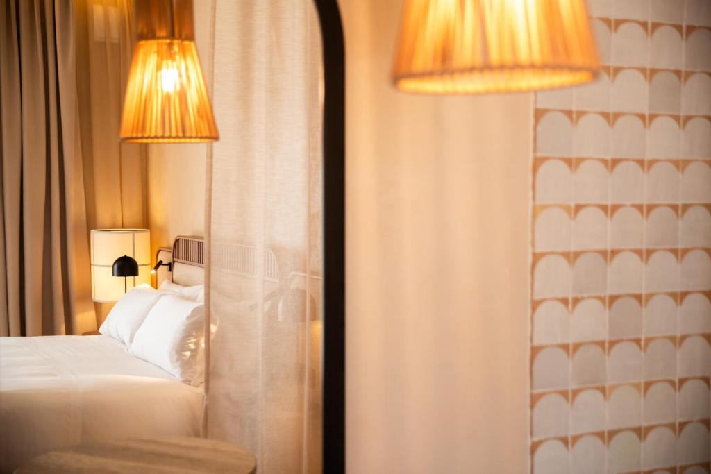 a bedroom with a bed and two lamps and a mirror at Cala Ponte, a Tribute Portfolio Hotel in Polignano a Mare