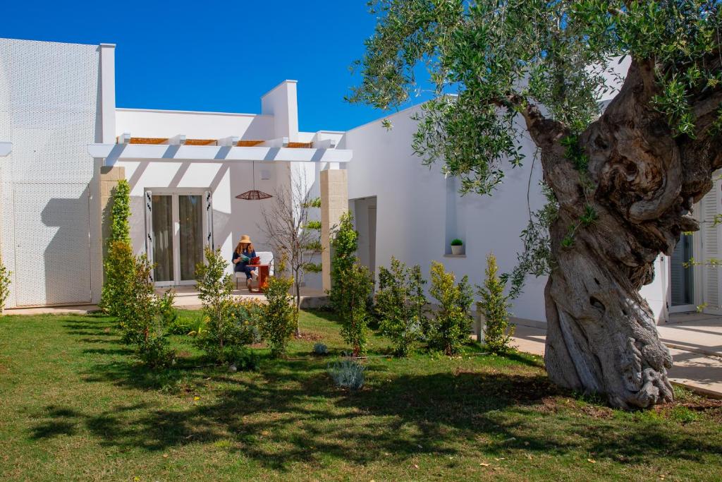 a white house with a tree in the yard at Cala Ponte, a Tribute Portfolio Hotel in Polignano a Mare