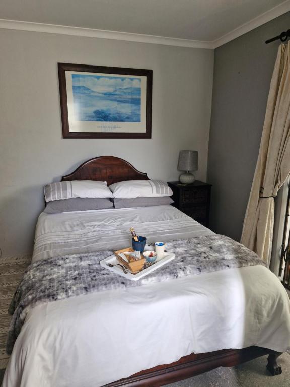 a bedroom with a bed with a tray of food on it at Mountain Rose Cottage in Bellville