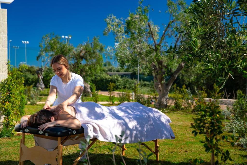 a woman is laying on a blanket on a table at Cala Ponte, a Tribute Portfolio Hotel in Polignano a Mare