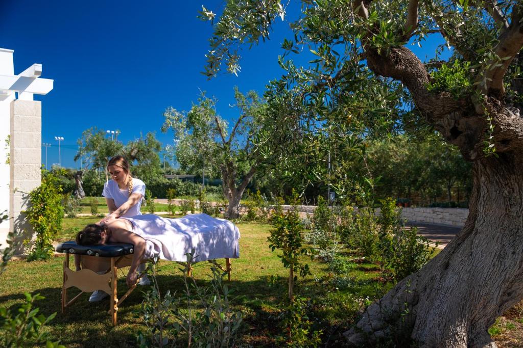 a woman standing next to a man laying on a bed at Cala Ponte, a Tribute Portfolio Hotel in Polignano a Mare