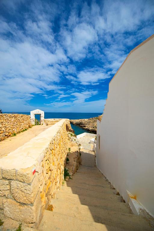a stone wall with a path next to a building at Cala Ponte, a Tribute Portfolio Hotel in Polignano a Mare