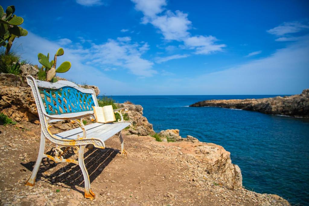 a bench sitting on the rocks near the ocean at Cala Ponte, a Tribute Portfolio Hotel in Polignano a Mare