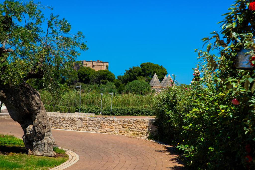 a brick road with a stone wall and a tree at Cala Ponte, a Tribute Portfolio Hotel in Polignano a Mare