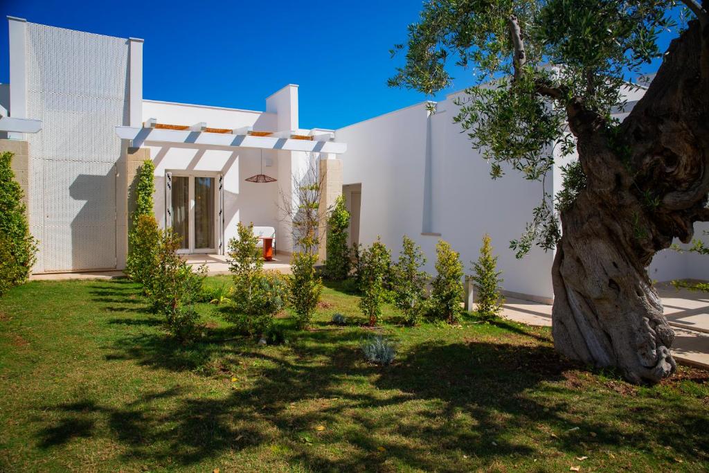 a white house with a tree in the yard at Cala Ponte, a Tribute Portfolio Hotel in Polignano a Mare