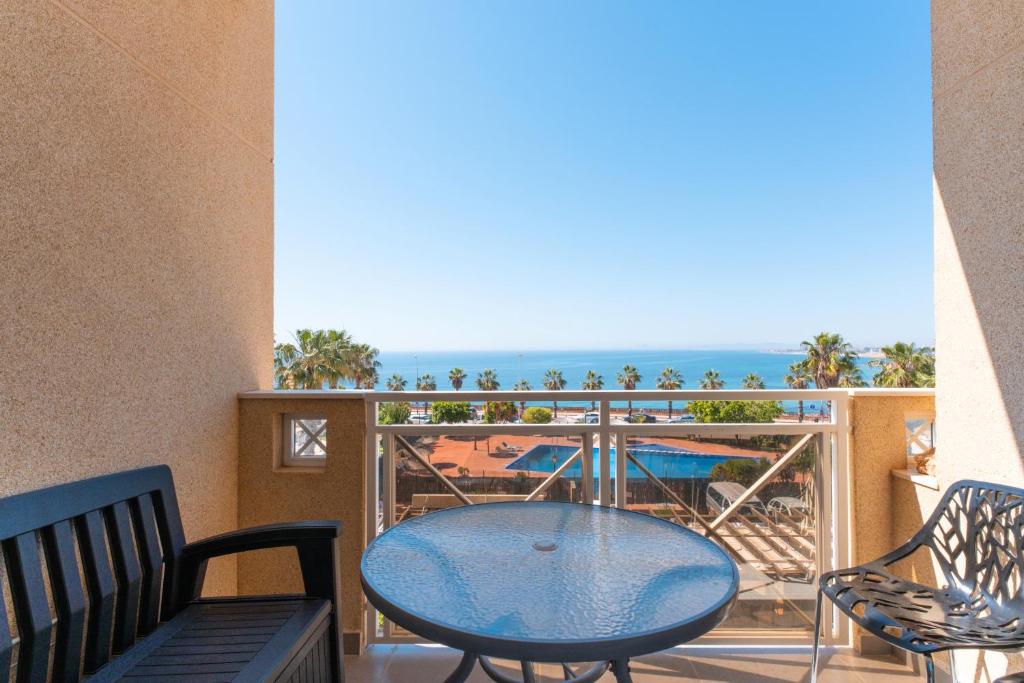Un balcón con mesa y sillas y el mar. en Casa del Sol Premium Cabo Roig, en Orihuela