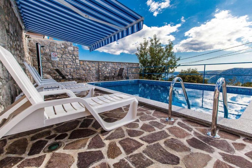 una piscina con 2 tumbonas junto a una piscina en Poolhouse Wowox, en Grižane