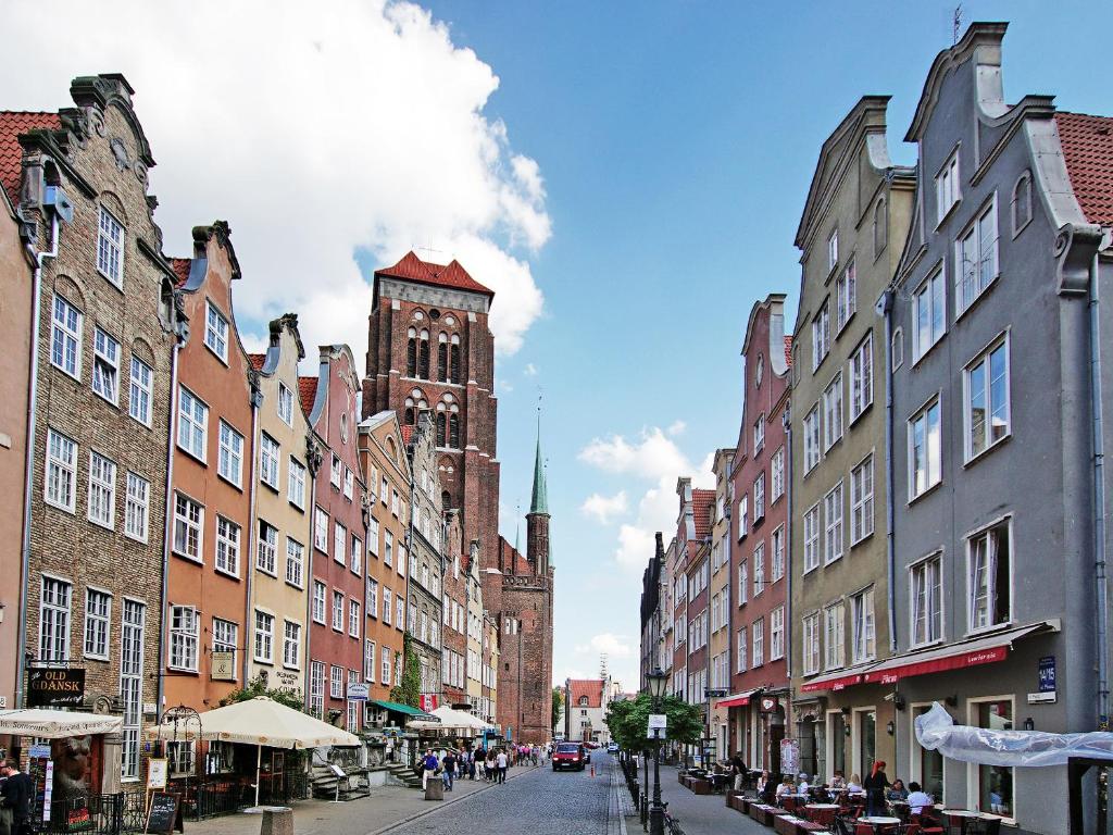 una via cittadina con edifici e una torre dell'orologio di Apartament Kameralny przy ul. Piwnej a Danzica