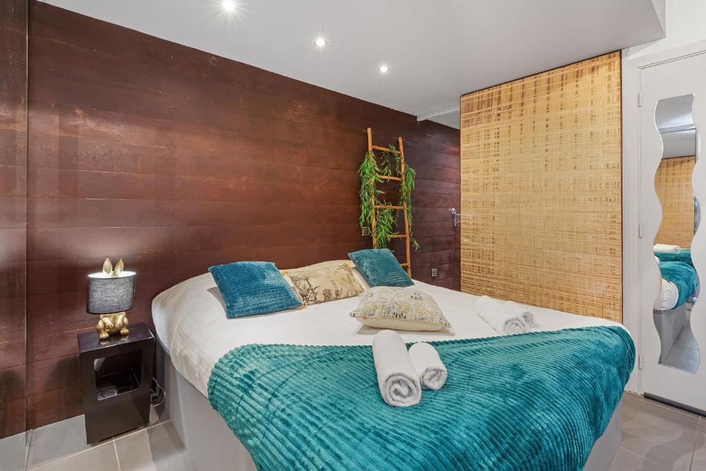 une chambre avec un grand lit avec des oreillers bleus dans l'établissement Village Naturiste R4N - Le Tikanah Port Nature, au Cap d'Agde