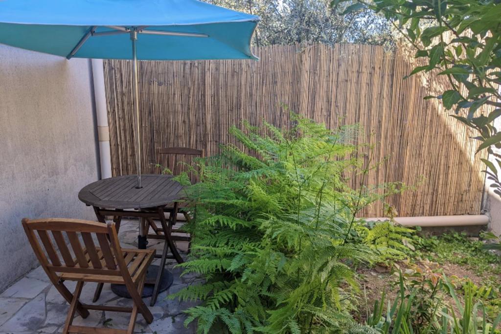 une terrasse avec une table et un parasol bleu dans l'établissement Charming studio near Nîmes center train station, à Nîmes