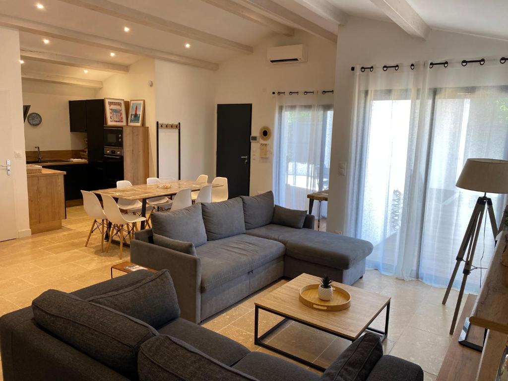 un soggiorno con un divano e un tavolo di Maison moderne plain-pied 3 chambres jardin préau a La Rochelle