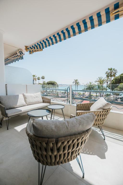 un balcon avec un canapé, des chaises et une table dans l'établissement T3 d'exception Croisette Cannes Vue Mer, à Cannes