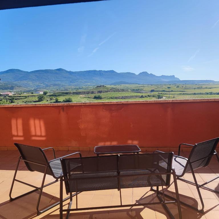 a table and chairs on a balcony with a red wall at Apartamento San Pelayo, LA PICUDA in San Vicente de la Sonsierra