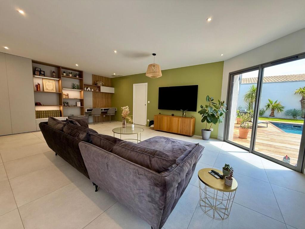 un grand salon avec un canapé et une télévision dans l'établissement Villa Palmeraie - Piscine, à Lagord