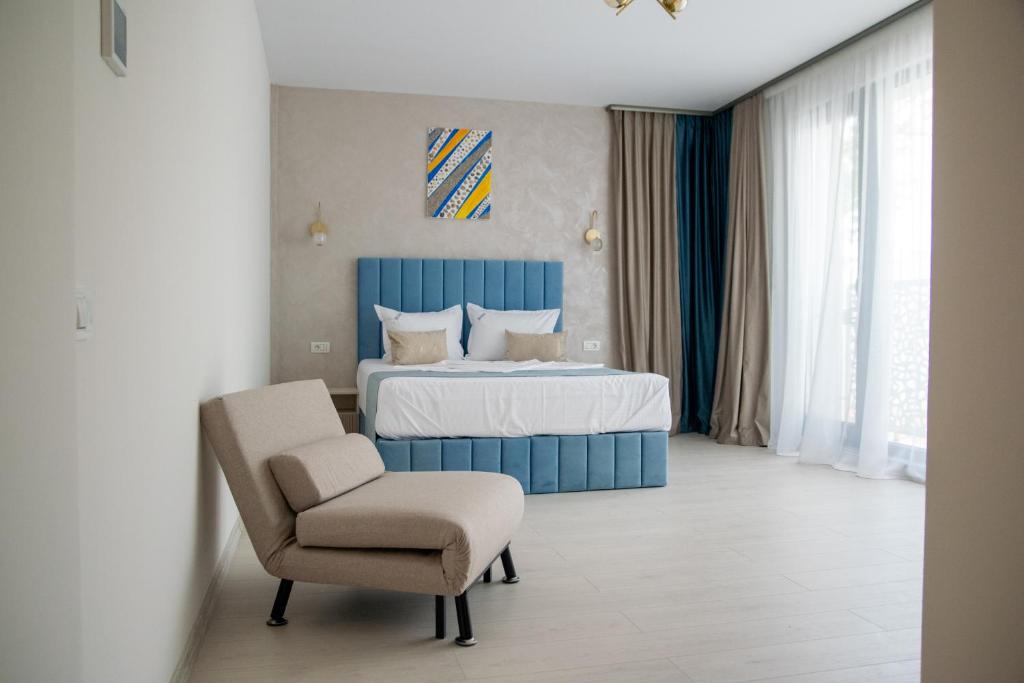 Un dormitorio con una cama azul y una silla. en Brizo Boutique Hotel, en Mamaia