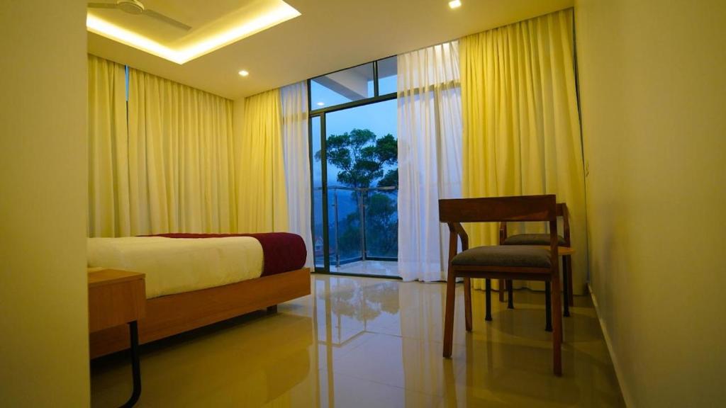 a bedroom with a bed and a chair and a window at Sunrise Munnar in Anachal