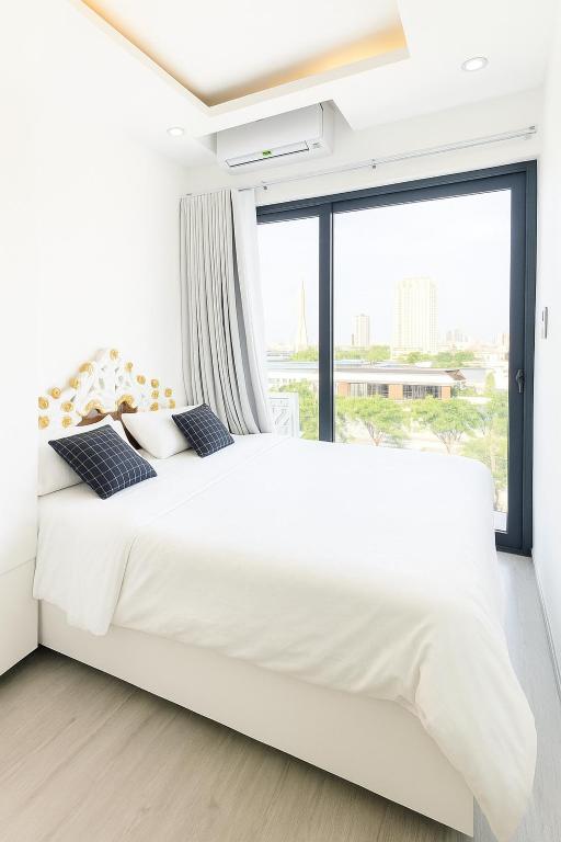 a bedroom with a large white bed with a large window at Louis Luxury Apartment & Hotel in Danang